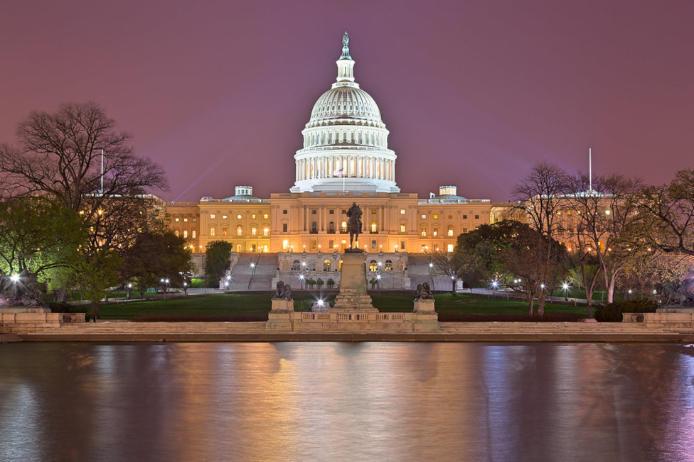 The US Capitol in front of a dusky pink sky, with the reflecting pool in the forgeround.